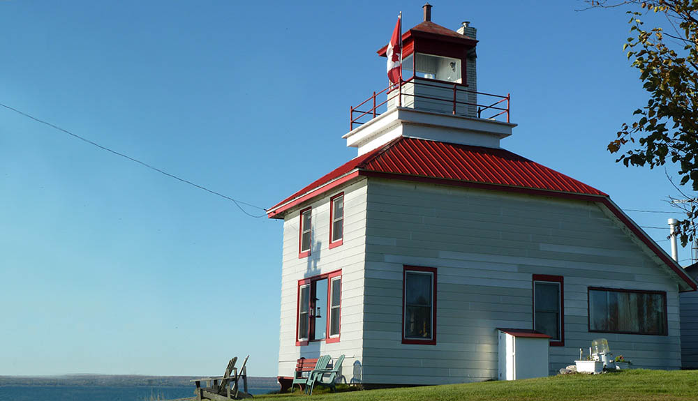 White and red lighthouse looks out at the ocean in Bruce Mines