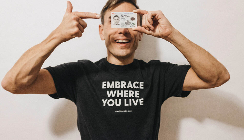 Comedian James Mullinger holding up his Canada permanent resident card