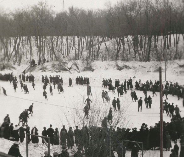 An old, black and white image of a crowd at an outdoor ice rink.