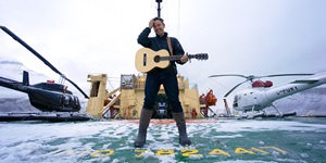 Danny Michel stands on a snowy platform with helicopters on either side of him