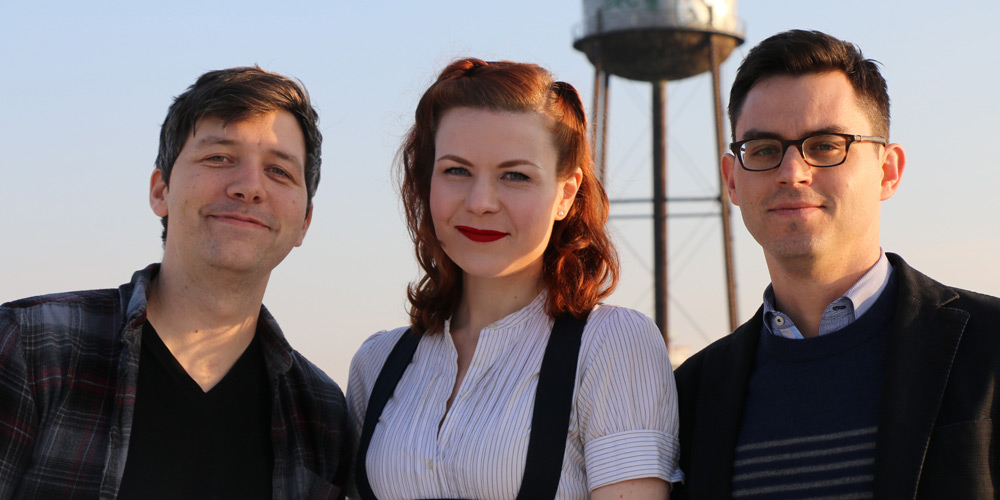 Dylan Thuras, Ella Morton and Joshua Foer ose smiling in front of a water tower