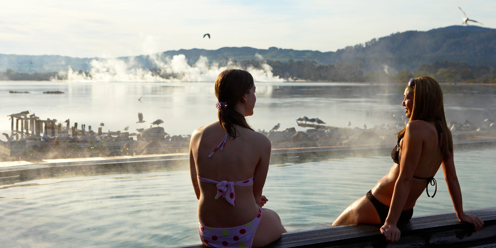 Two women soaking their legs at the hot springs in New Zealand