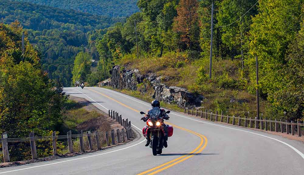 A red motorcycle zips along the lush, hilly roads of the Deep Valley run trail