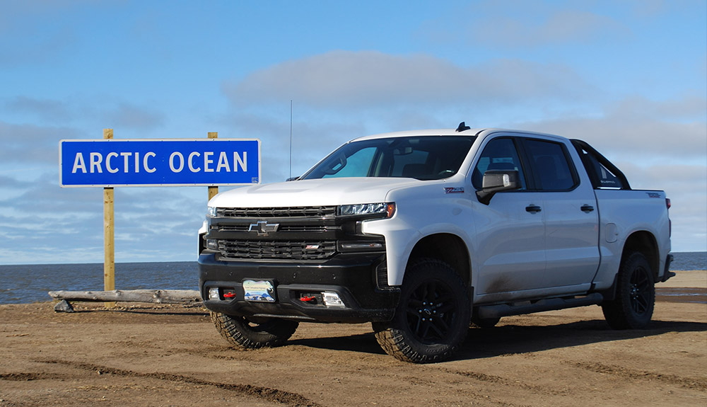 White Ford truck parked in front of sign that reads Arctic Ocean near waterfront