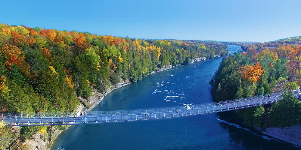 The Double Trestle Bridge stretches across a river lined with trees showing fall colours