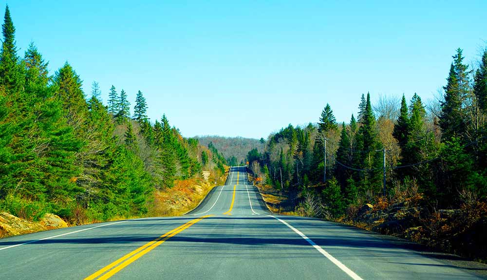 The empty, tree-lined road of Highway 60 going through Algonquin Park in Ontario