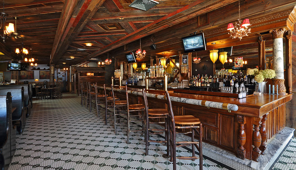 A cozy bar with interesting tiled floor, wooden bar and stools and warm lighting in Elicottville, New York