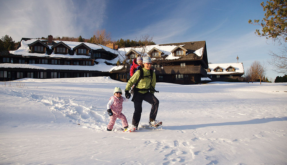 Father and daughter horseshoeing in fresh winter snow in front of a ski lodge in Vermont