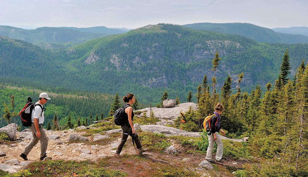 A group of people hiking over rocks and hills in Grands-Jardins National Park in Quebec