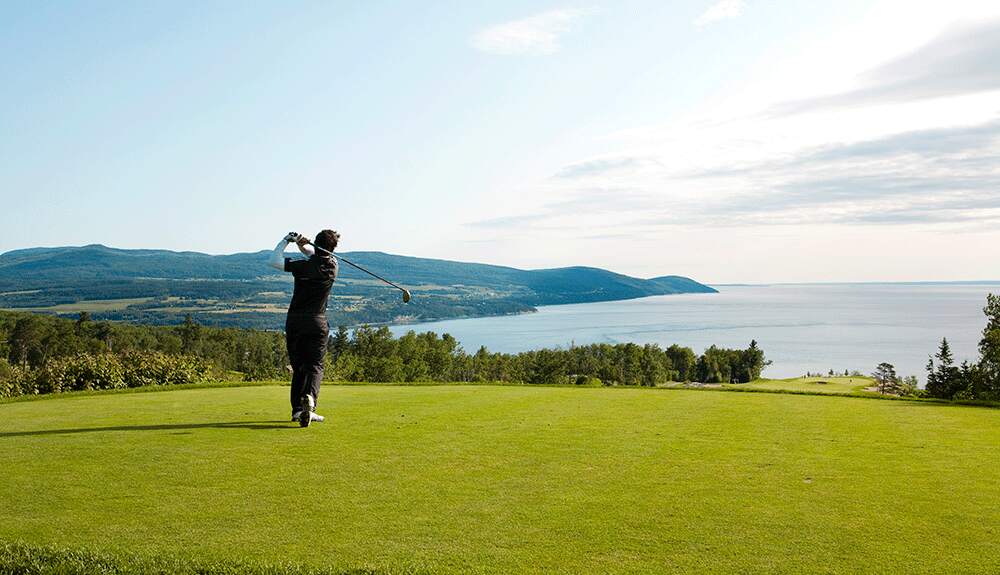 A man swinging a golf club on one of the courses at Fairmont Le Manoir Richelieu in Quebec