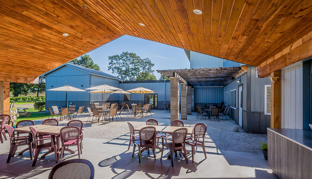 Beautiful patio at Johnson Estate Winery with many large tables, umbrellas and a wooden bar