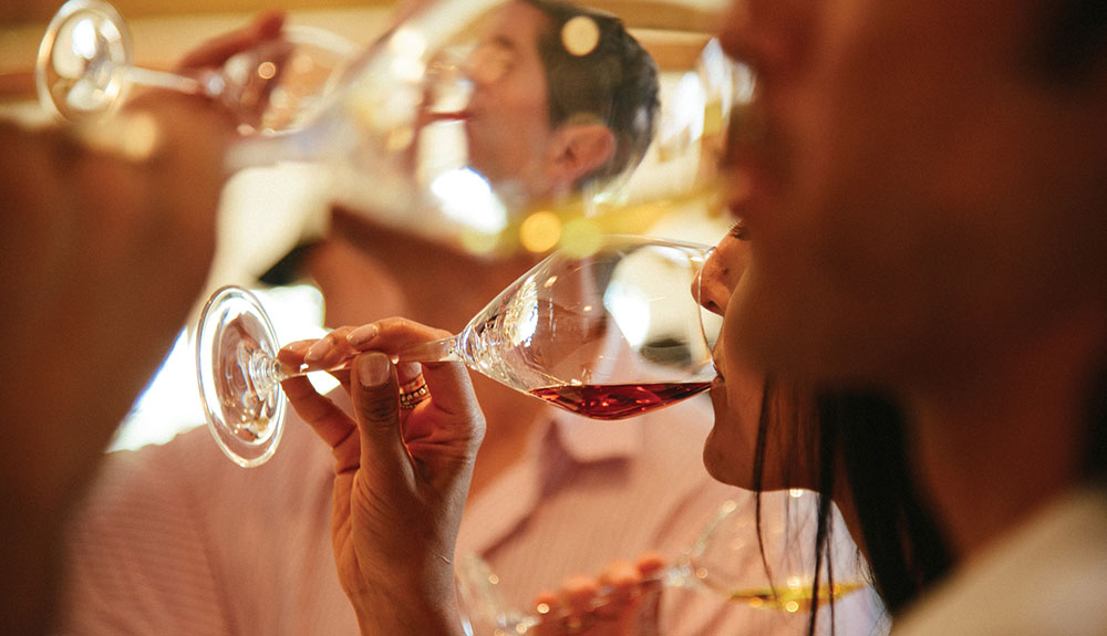 Three young adults tasting red and white wines