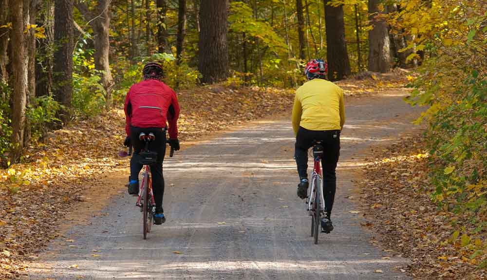 Two cyclists are shown on a bike path in the Kawarthas Northumberland region in the fall