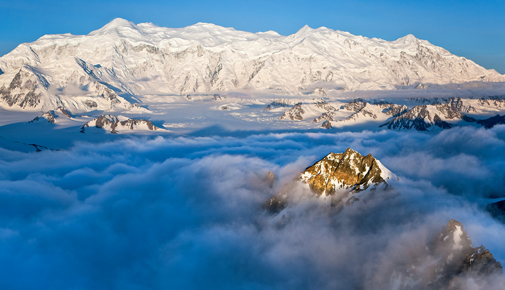 Snow-topped mountains are shown just above the clouds