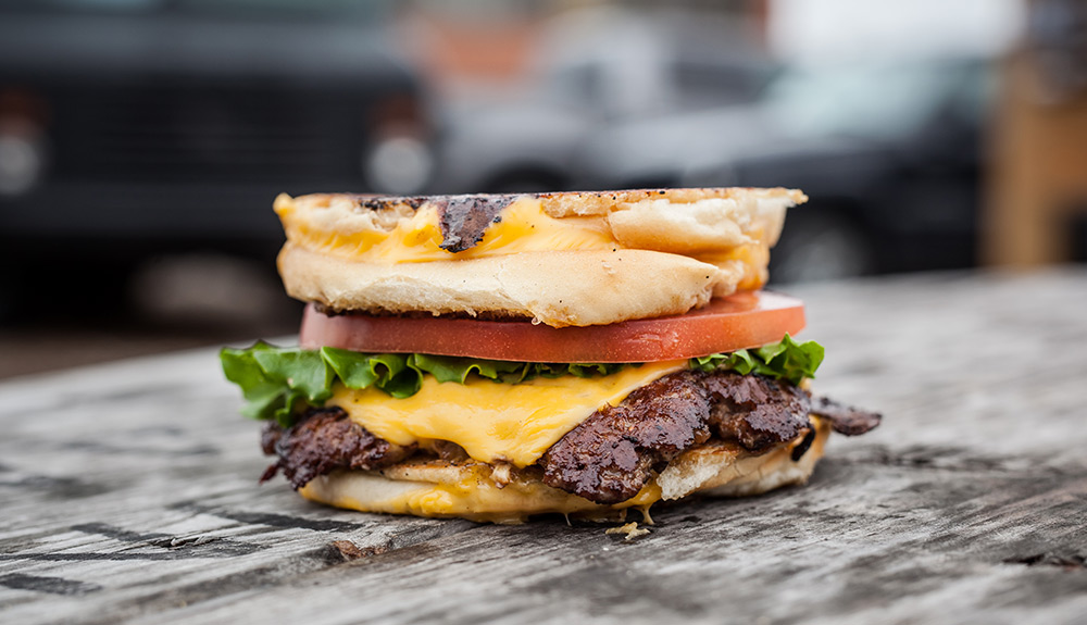 Delicious Burger Rebellion burger with cheese, lettuce and tomato on a fried bun 
