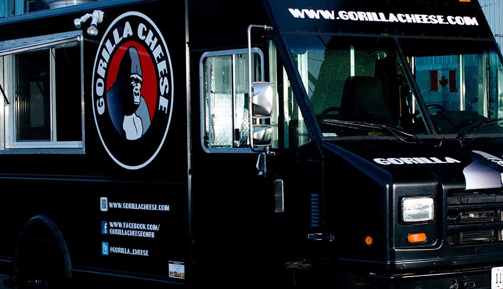 The black food truck of Gorilla Cheese with the company logo seen on the side