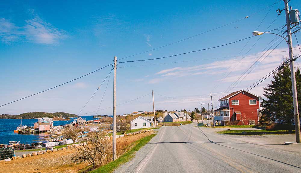 A quiet highway beside a classic east-coast town, the waterfront seen on one side and quaint buildings on the other