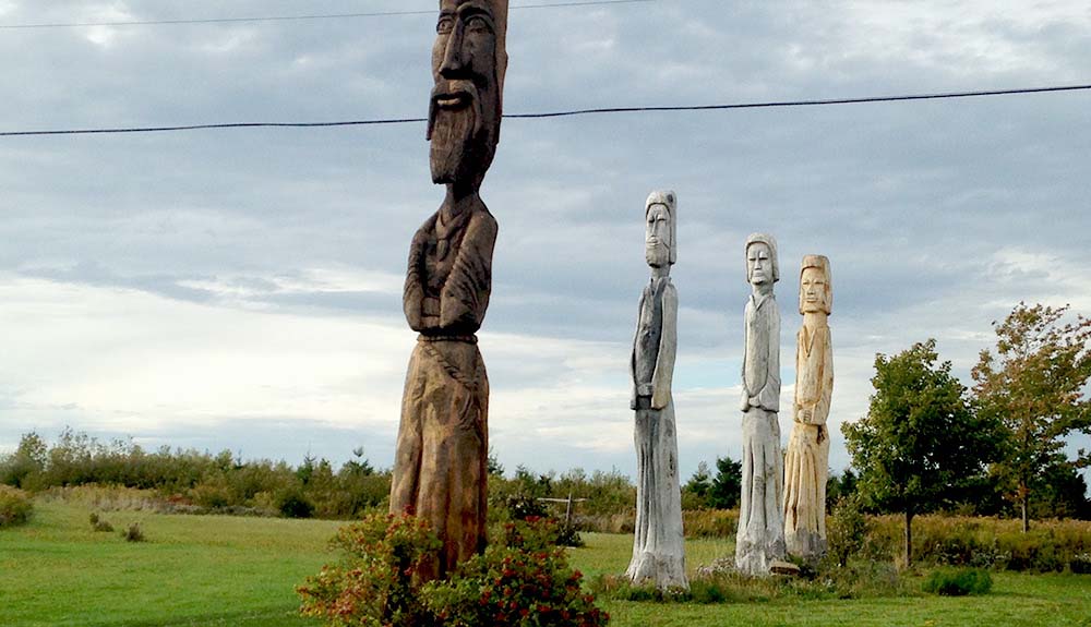 Four towering Easter Island-like statues carved out of the trunks of once-living trees stand tall near Big Island in Nova Scotia