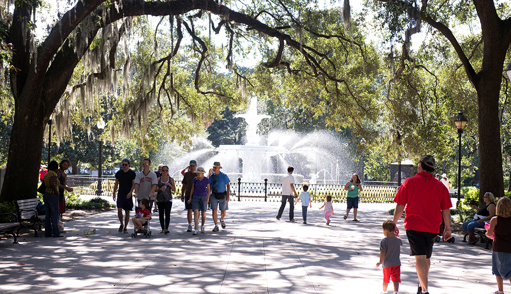 Happy families stroll under trees beside a gorgeous fountain at Forsyth Park in Savannah