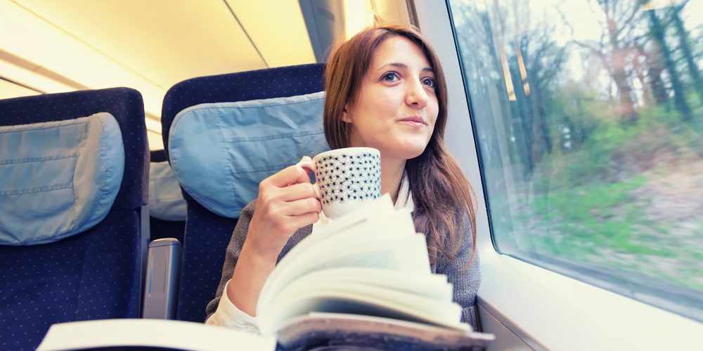 Woman sipping tea and looking out train window