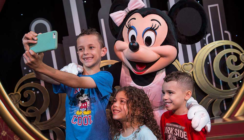 Little boy taking a selfie with Minnie Mouse and two other kids