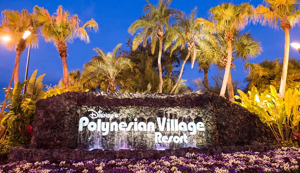 Polynesian Village resort sign at night surrounded by palm trees