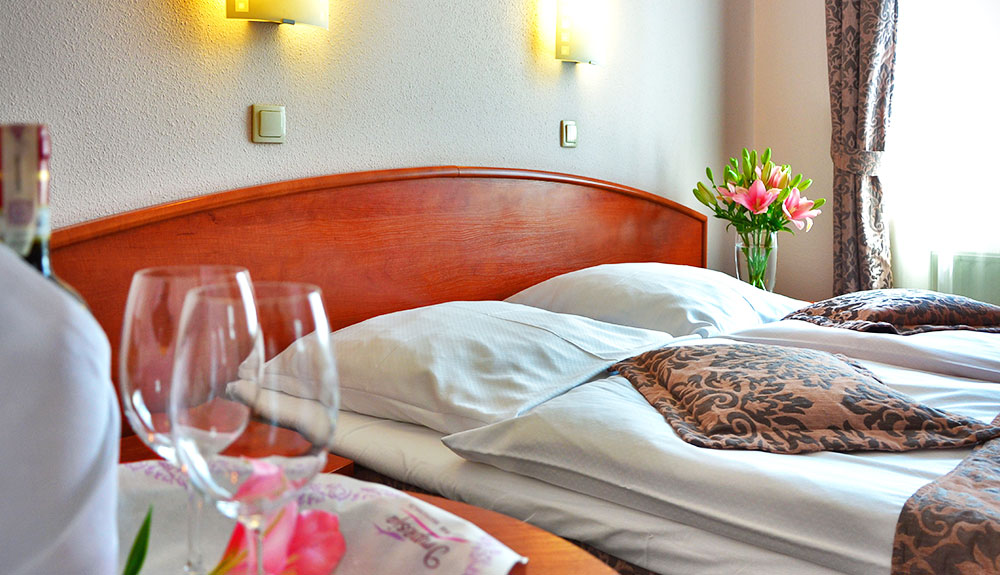 Hotel bed, fresh flowers on the night stand and the window opened filling the room with daylight