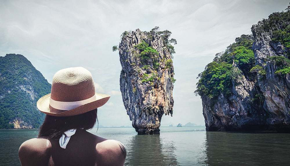 Woman with a straw hat on a boat approaching a floating island in Thailand