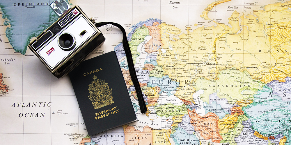 World map with a camera and Canadian passport on top