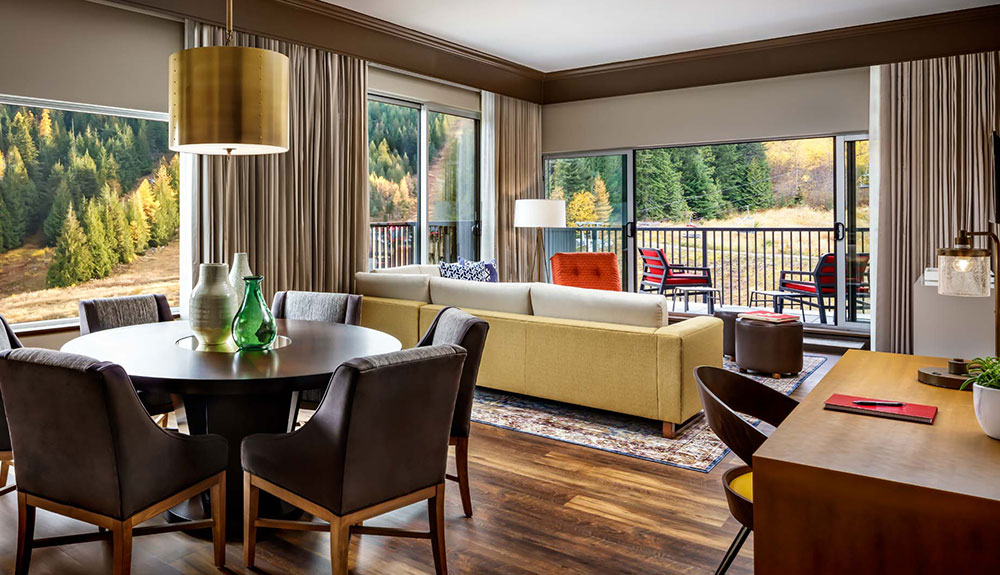 Suite of the new boutique ski-in, ski-out property featuring a table with chairs, a desk and chair and the back of a couch