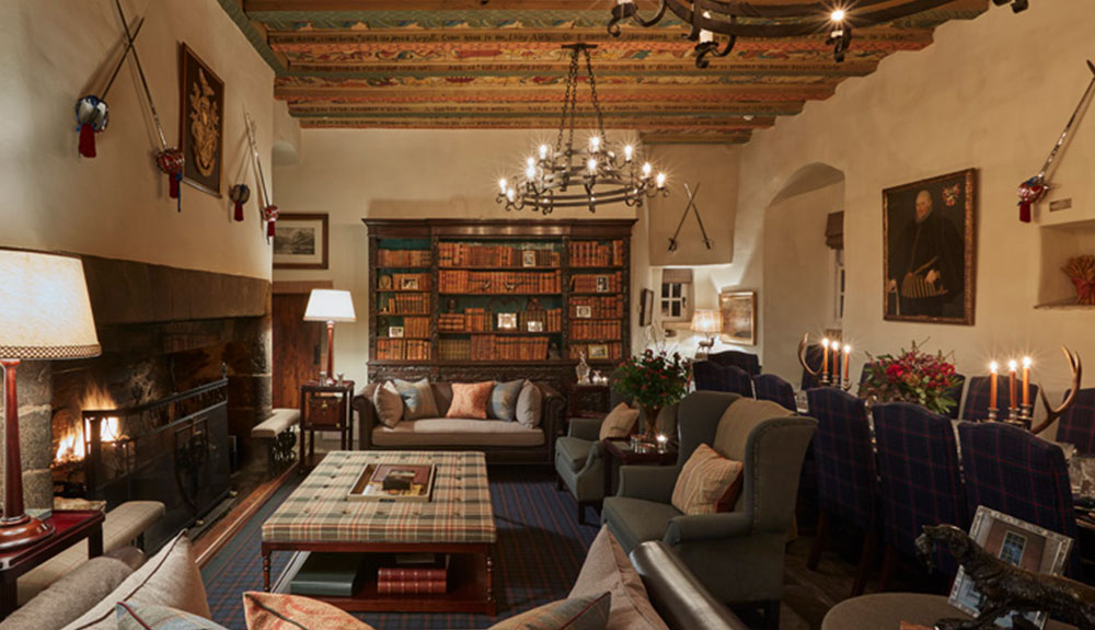 Inside the Forter Castle in Scotland featuring a large fireplace, multiple couches and a dining room behind them
