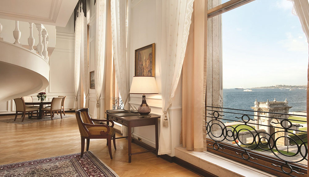Inside the restored former Ottoman palace with a winding staircase, desk and chair and window with a view of the water and archway outside