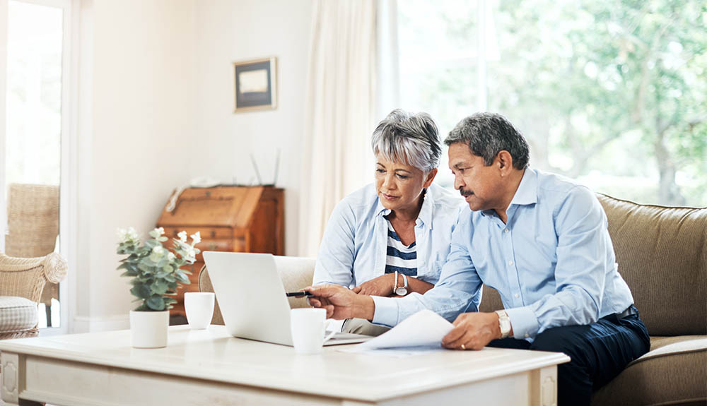 Older couple sitting on couch looking at laptop