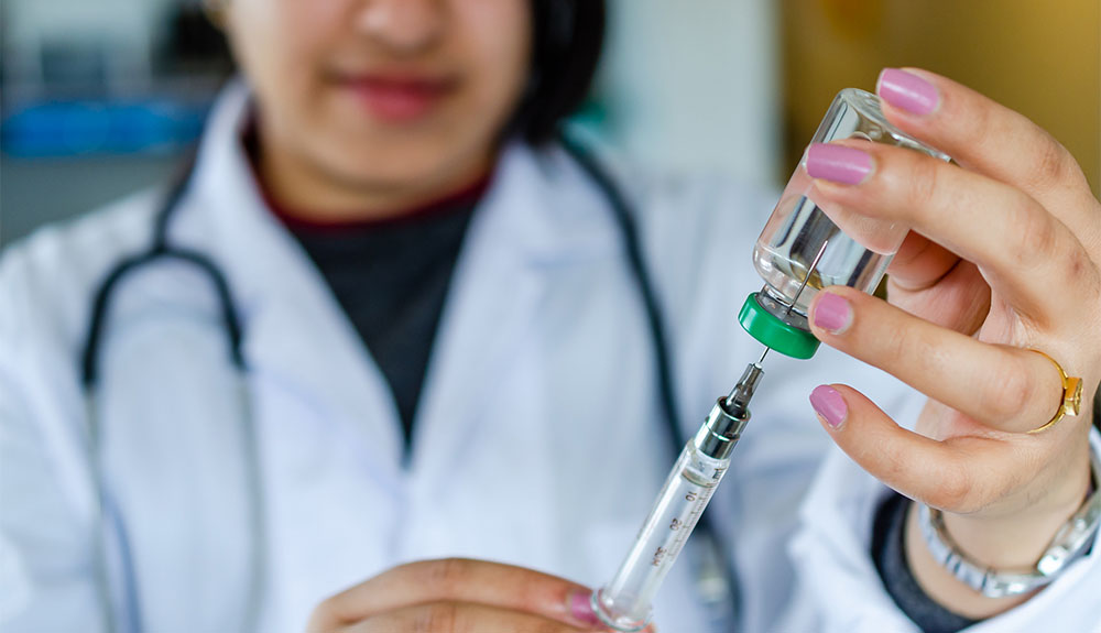 Doctor filling syringe from glass container