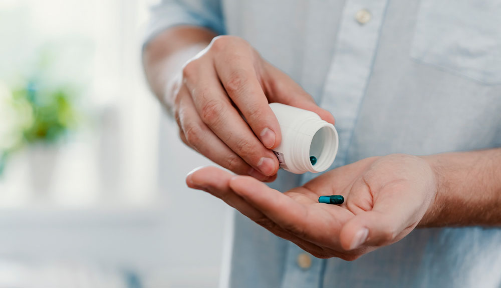 Person shaking pills from a container into their palm