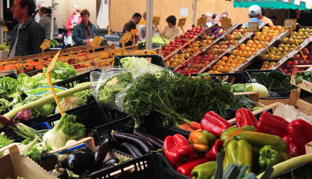 Red and green peppers, eggplants, carrots and other vegetables bunched together at a farmer' market