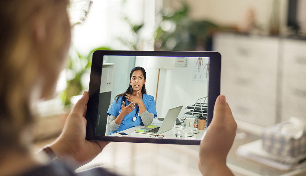 Person looking at tablet screen showing videoconference with doctor