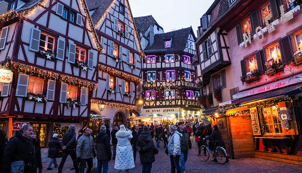 European street decorated for Christmas filled with pedestrians in the early evening