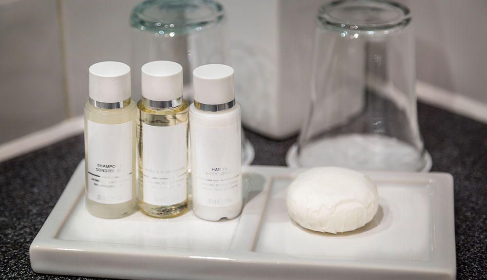 Hotel-supplied toiletries and water glasses are shown on a tray