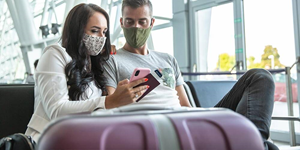 Young couple checking their cell phone in an airport lounge.
