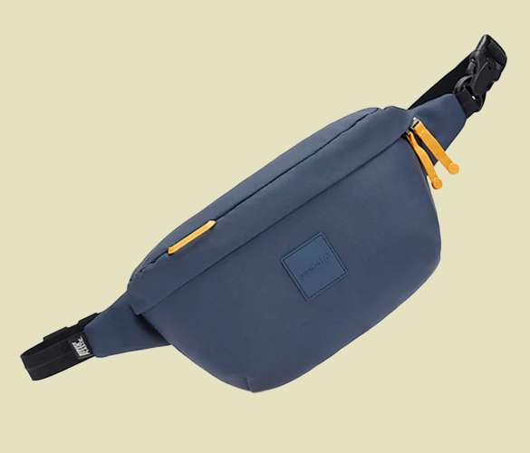 A dark blue fanny pack with yellow zippers and black straps in front of a beige background.