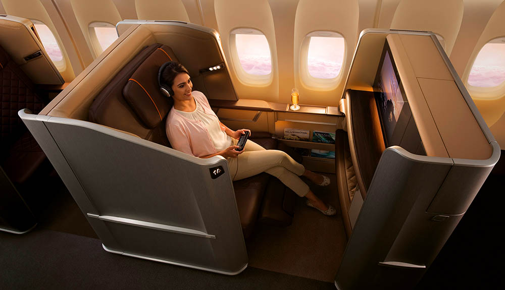 A woman sits in the private seating pod on Singapore Airlines, enjoying watching a film on the large screen