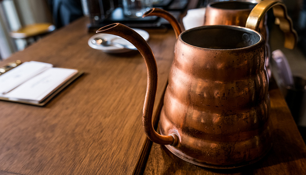 A brass tea pot with a long stem