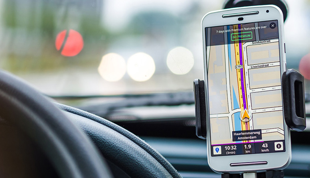 A smartphone is mounted to a car dash, open to a map app