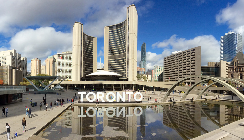 The city center of Toronto, Ontario, the large city sign lit up, tall buildings seen behind it