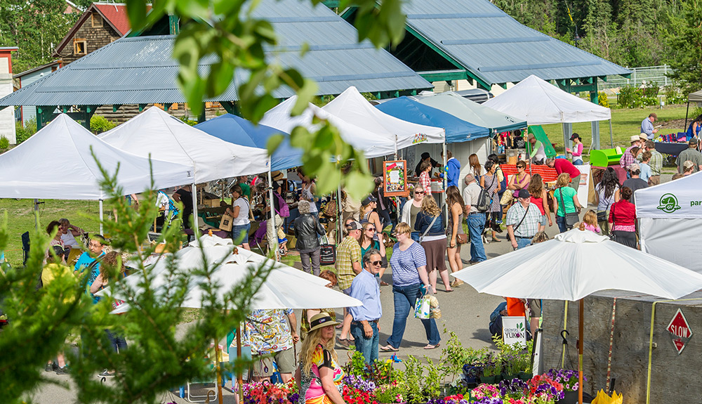 A crowd of people check out booths under white tents in Whitehorse, Yukon