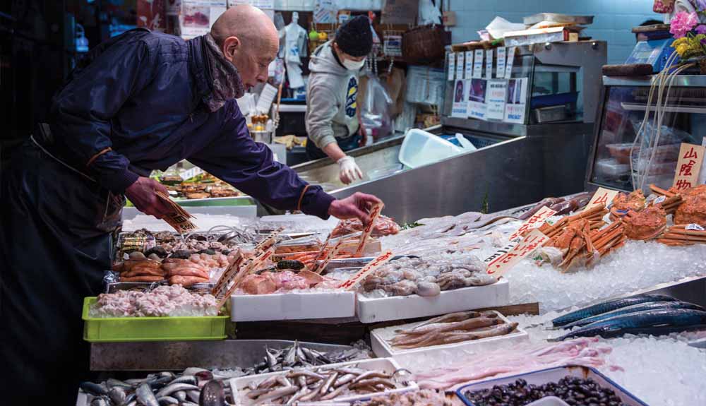 A man lays out fresh seafood on ice at a stall in Kyoto market