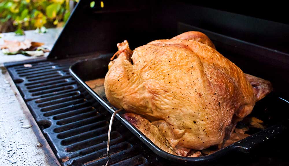 Turkey being cooked on the grill of a barbecue
