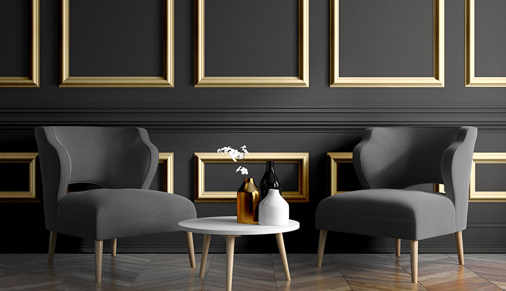 Dark grey living room with wood panelling painted a striking gold, monochromatic grey chairs with gold legs in the same shades and a white and gold side table
