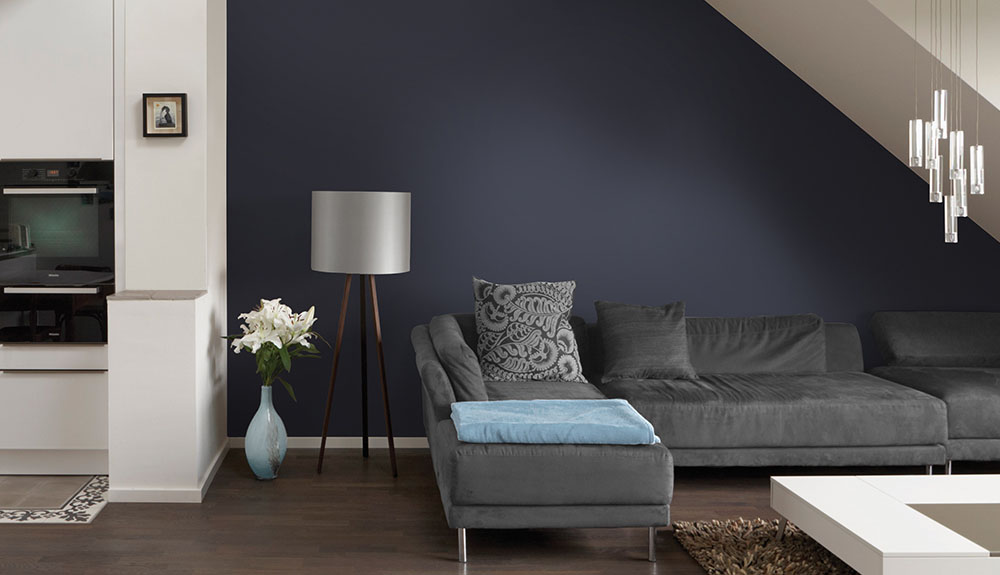 A dark blue living room with dark grey couch that pairs well with wall colour